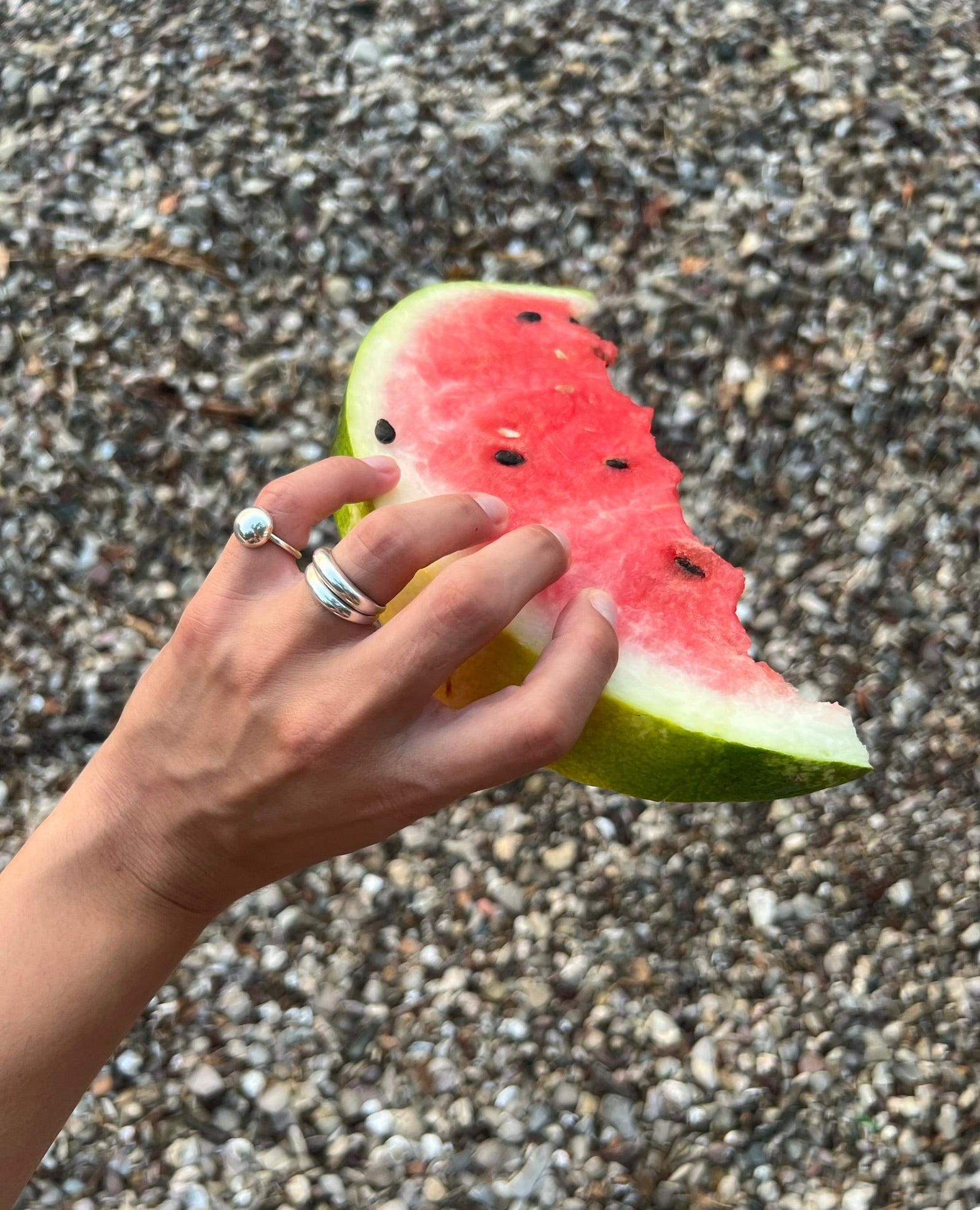 Hand full of rings holding a slice of watermelon